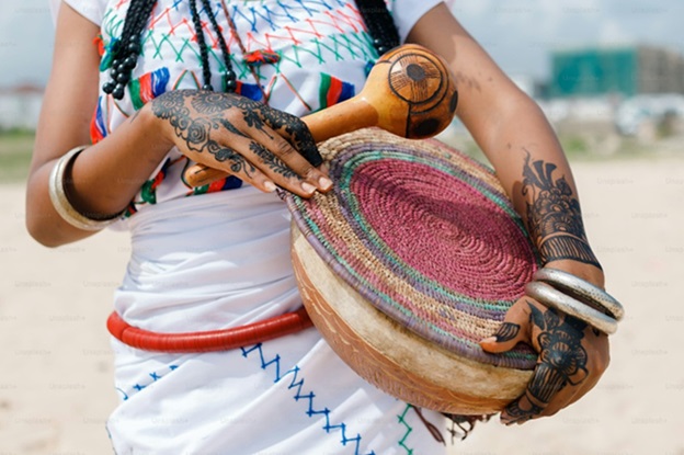 A woman holding a large drum on a beach